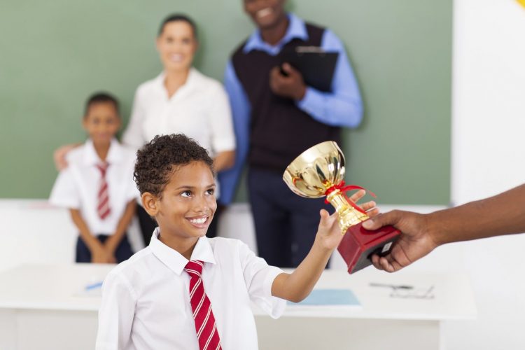 school boy receiving a trophy in classroom