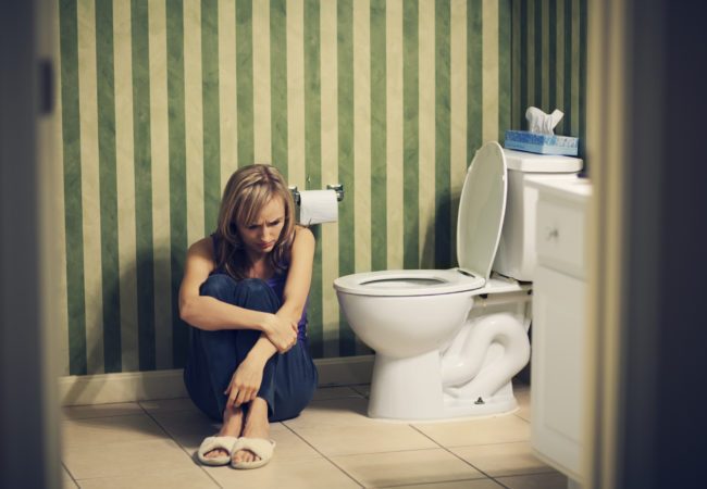 Sad young woman in bathroom during postpartum recovery period