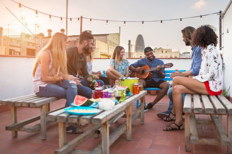 Party of friends around table playing music at dusk