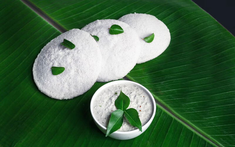 Idli and coconut chutney on banana leaf